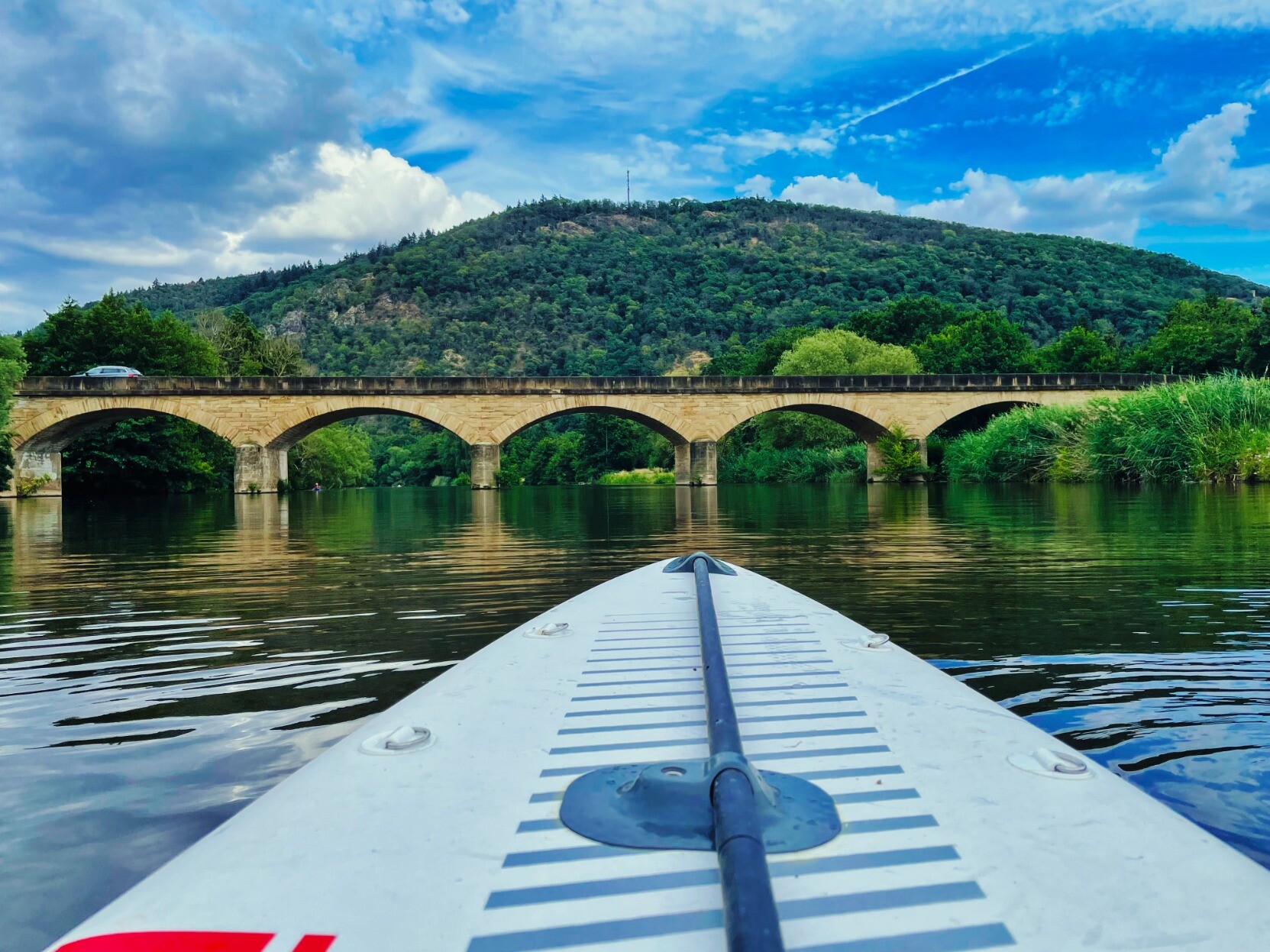 Man sieht die Spitze eines Red Paddle Race-SUP auf der Nahe, mit Blick auf die Luitpold-Brücke im schönen Oberhausen an der Nahe.